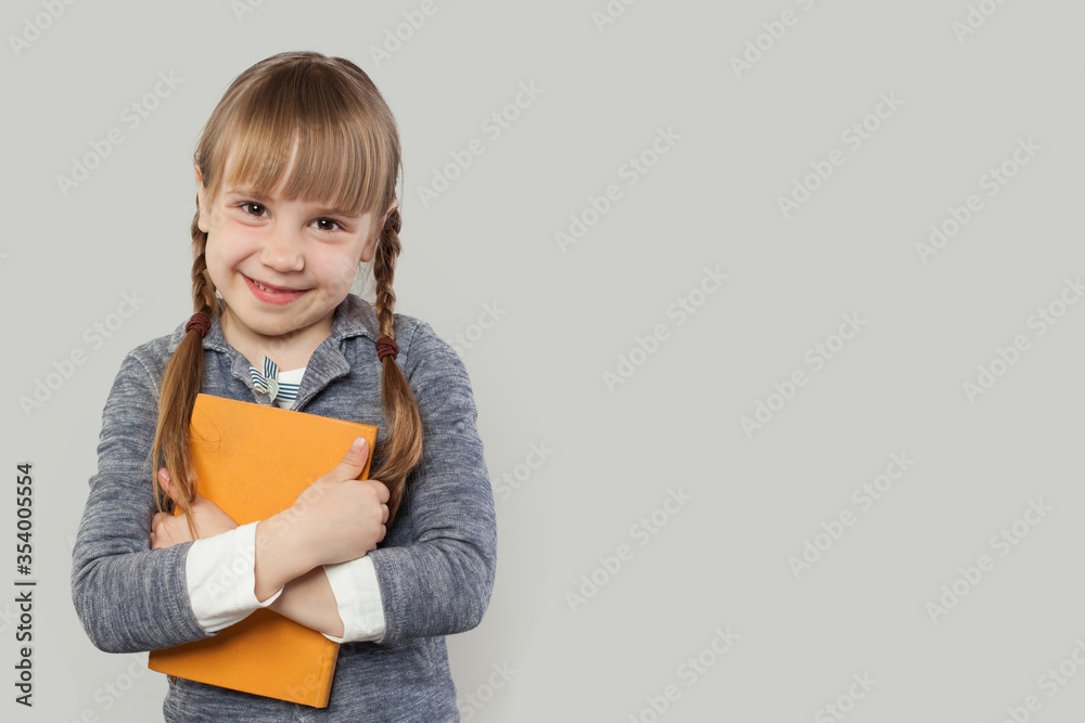 Happy child girl in school uniform clothes with book on white background. Back to school, elementary school lesson and education concept Happy child girl in school uniform clothes with book on white background. Back to school, elementary school lesson and education concept