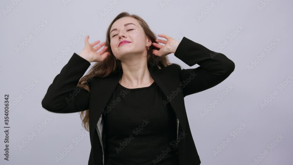Young Attractive Woman Brunette In In A Black T-Shirt And Sweater On White Background, Happy Female Smiles, Shakes Hair With Hand, Adjusts Her Hairstyle. The Concept Of Cool, Modern People, Body Care Young Attractive Woman Brunette In In A Black T-Shirt And Sweater On White Background, Happy Female Smiles, Shakes Hair With Hand, Adjusts Her Hairstyle. The Concept Of Cool, Modern People, Body Care