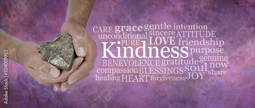 Heart felt Kindness Concept  Word Cloud - male hands gently cupped around a wooden heart beside a  Kindness word tag cloud against a wide rustic pink  grunge background
