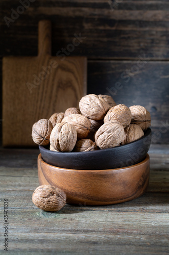 Walnuts in round bowl on wooden rustic background 