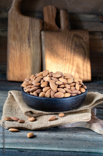 Almonds in round bowl on rustic wooden background 