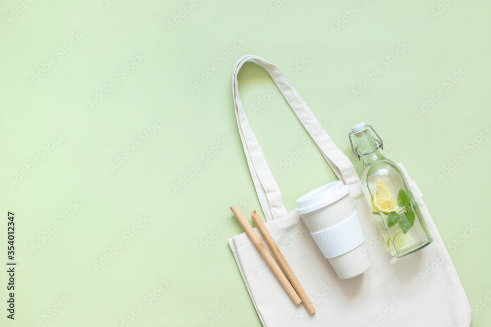 Cotton bag, thermos, glass bottle with lemon water and Melissa bamboo tubes. Let's go shopping. Ecological, natural materials.