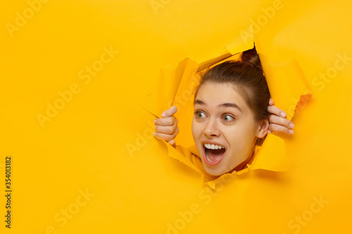 Tableau sur toile Young excited girl looking through hole in paper at beneficil commercial offer w