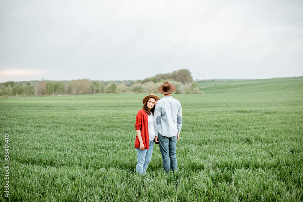 Portrait of a lovely couple standing together on the greenfield. Happy couple expecting a baby, young family concept Portrait of a lovely couple standing together on the greenfield. Happy couple expecting a baby, young family concept