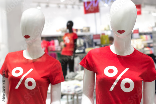 Two female mannequin in red t-shirts with sign "%". White dummies with red lips. Advertising and sale of clothes, sell-out, seasonal discounts, black friday. Fashion business