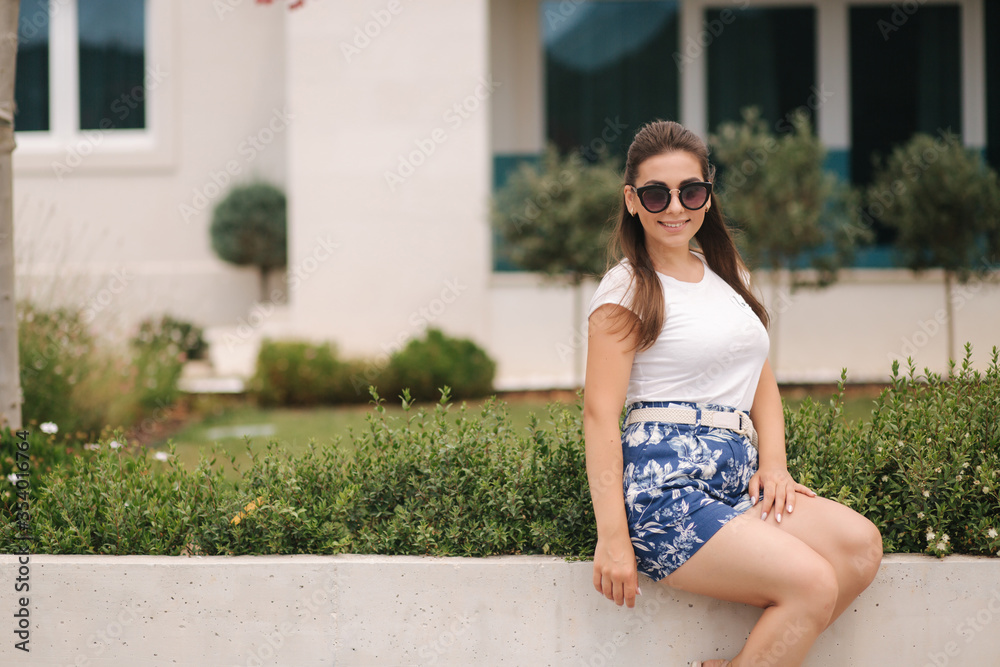 Attractive woman sits by the house in summer time. Beautiful young woman have a rest in front of her house Attractive woman sits by the house in summer time. Beautiful young woman have a rest in front of her house