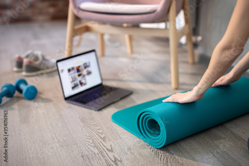 Young sporty slim woman preparing for online fitness training with modern laptop. Healthy lifestyle concept, online fitness and sport lessons. 