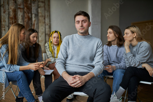 stressful caucasian male is member of alcoholics club, he want to get rid of addiction, sit apart from club and look at camera