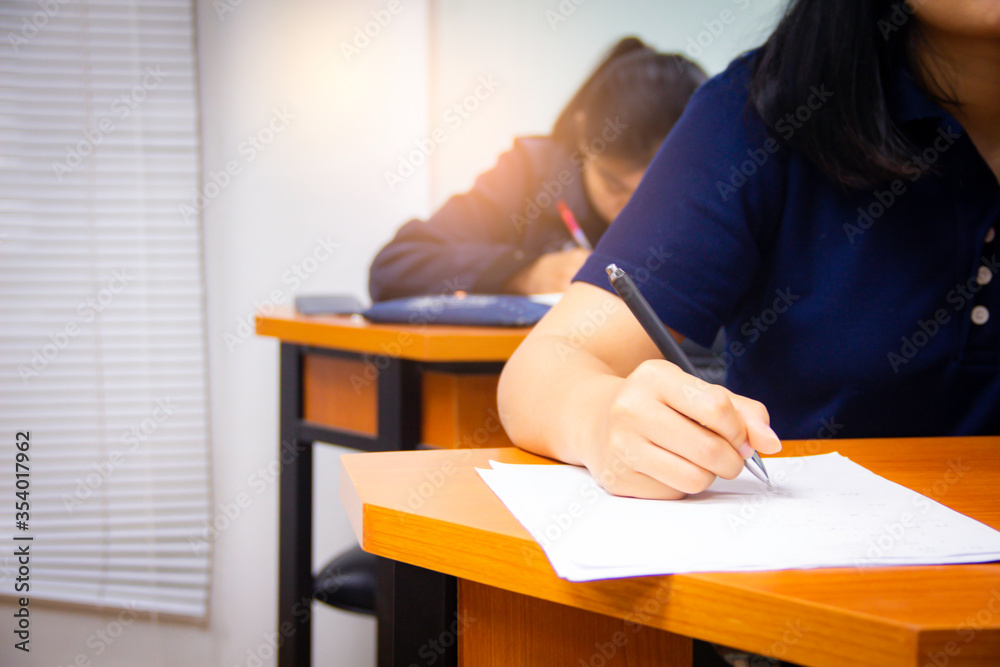 Hands university student holding pen writing /calculator doing examination / study or quiz, test from teacher or in large lecture room, students in uniform attending exam classroom educational school. Hands university student holding pen writing /calculator doing examination / study or quiz, test from teacher or in large lecture room, students in uniform attending exam classroom educational school.