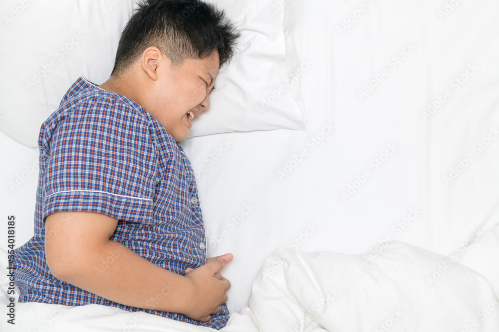 asian child suffering from stomachache and lying on bed top view s asian child suffering from stomachache and lying on bed top view s
