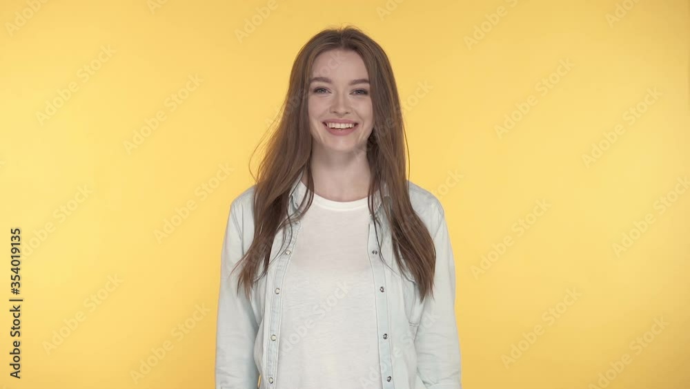 Smiling young woman looking at the camera. Yellow background. Smiling young woman looking at the camera. Yellow background.