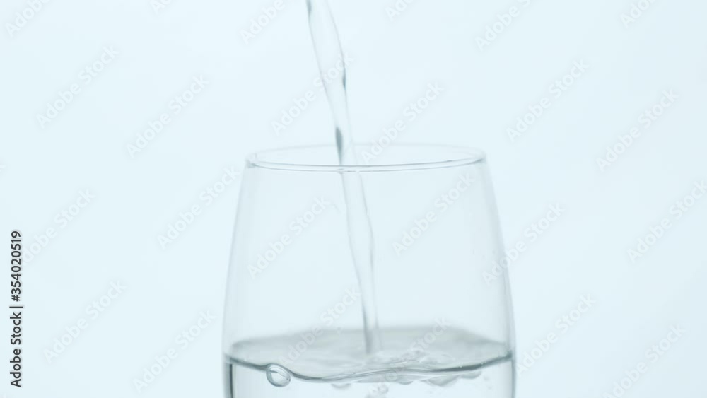 A glass of clean water on a white background close-up. Water is pouring into a glass. Slow motion. A glass of clean water on a white background close-up. Water is pouring into a glass. Slow motion.
