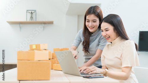 Startup small business owner working with computer at workplace. Freelance two woman seller check product order. Packing goods for delivery to customer. Online selling. E-commerce. Online Shopping 