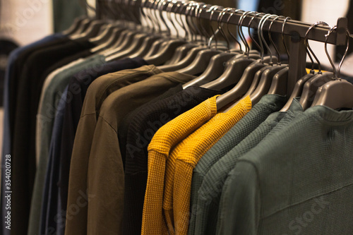 group of multi-colored sweaters hanging trempels in a fashion boutique for sale