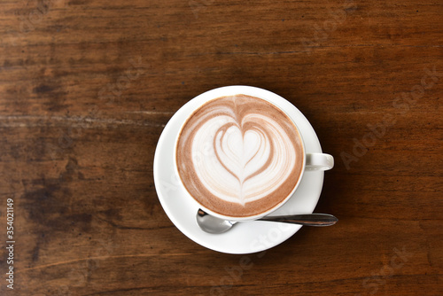 Coffee cup with Latte art on wooden table menu in coffee break time.Latte art froth design pattern is a method of preparing coffee.