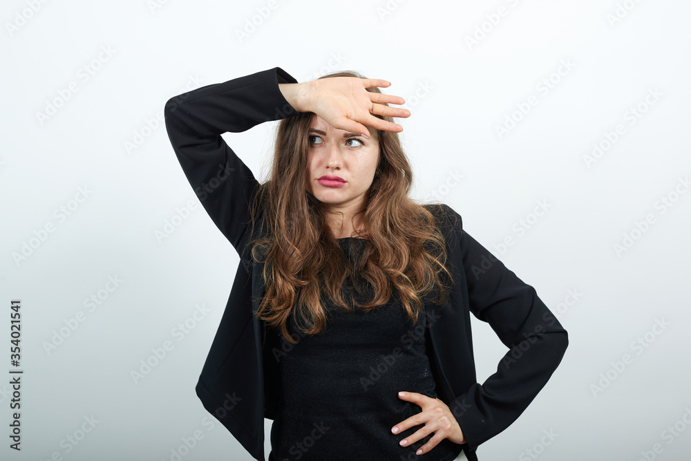 Young Attractive Woman Brunette In In Black T-Shirt, Sweater On White Background, A Tired Woman After Work Holds Hand On Her Forehead. The Concept Of Physical And Mental Fatigue Young Attractive Woman Brunette In In Black T-Shirt, Sweater On White Background, A Tired Woman After Work Holds Hand On Her Forehead. The Concept Of Physical And Mental Fatigue