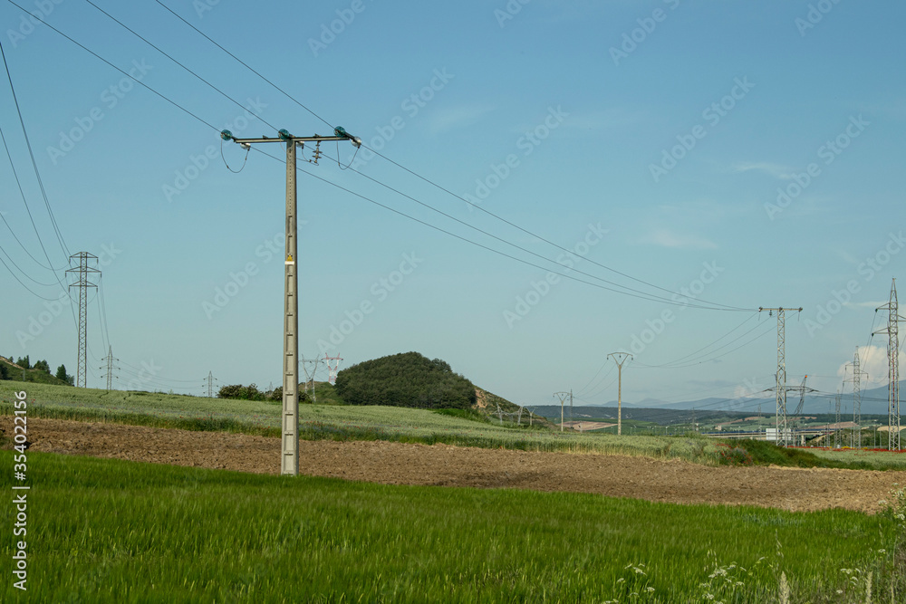 Paisaje de prados verdes en verano con tendido eléctrico.