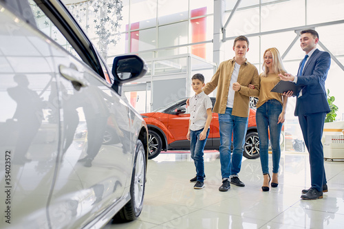 beautiful caucasian family have conversation with affable pleasant salesman in dealership, get consultation before purchase