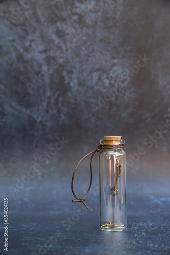 Romantic retro vintage glass wish bottle with good luck charm inside bottle wth cork topper and antique effect background