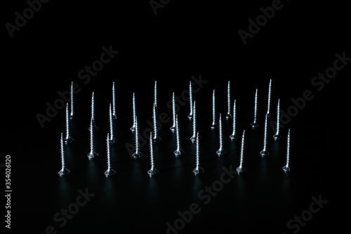 Zinc plated wood threaded screws standing in formation on black background