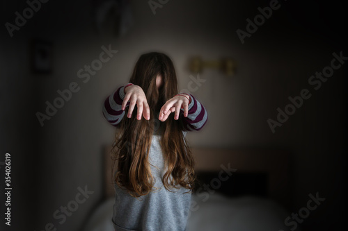 Canvastavla A little girl with long hair is standing in the room like a zombie