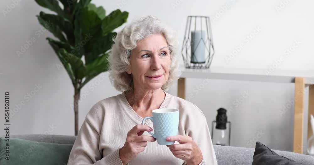 Dreamy relaxed older 70s retired beautiful woman drinking coffee, enjoying good morning time alone at home. Happy mature senior grandmother thinking of future, planning weekend day with good mood. Dreamy relaxed older 70s retired beautiful woman drinking coffee, enjoying good morning time alone at home. Happy mature senior grandmother thinking of future, planning weekend day with good mood.