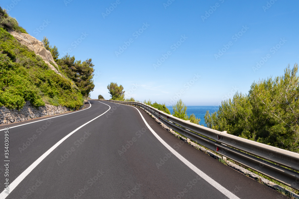 Empty curved coastal road on sunny day