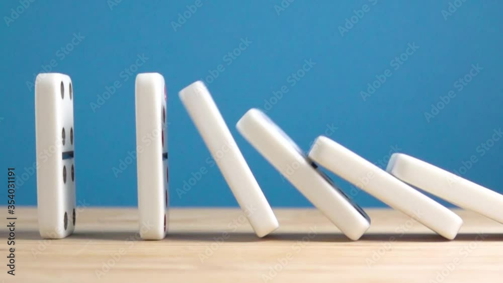 Dominos falling in slow motion. Close up of domino effect. Concept of chain reaction.