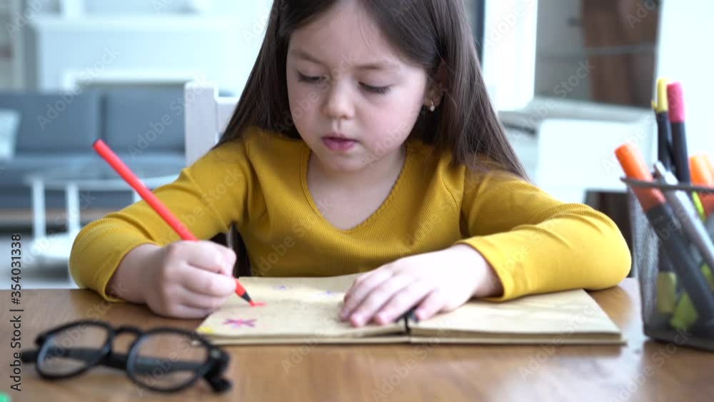 Cute smart primary school child girl learning writing doing homework sit at home table, adorable pretty little preschool kid studying alone making notes, children elementary education concept Cute smart primary school child girl learning writing doing homework sit at home table, adorable pretty little preschool kid studying alone making notes, children elementary education concept