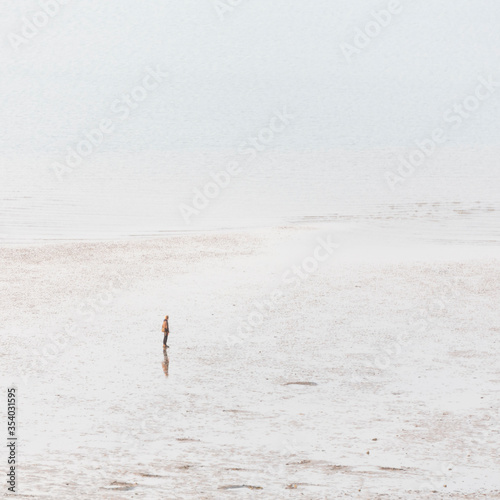 A man standing alone on Tankerton Beach, Whitstable, England photo