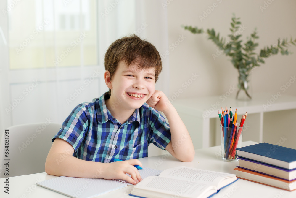 boy is sitting at the table, writing in a notebook, laughing boy is sitting at the table, writing in a notebook, laughing