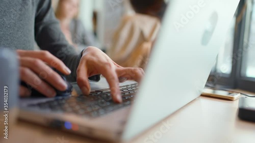 Closeup of womans fingers typing laptop keyboard and using computer mouse. young woman using laptop photo