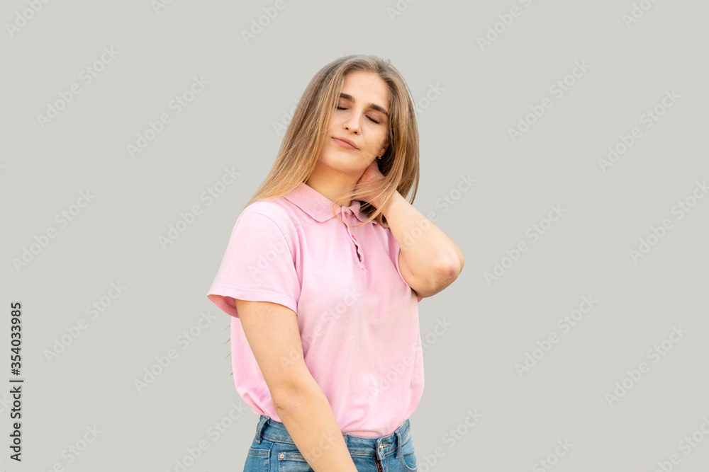 The young girl thought about something with her eyes closed. Dressed in a pink T-shirt. Isolated on gray background. The young girl thought about something with her eyes closed. Dressed in a pink T-shirt. Isolated on gray background.