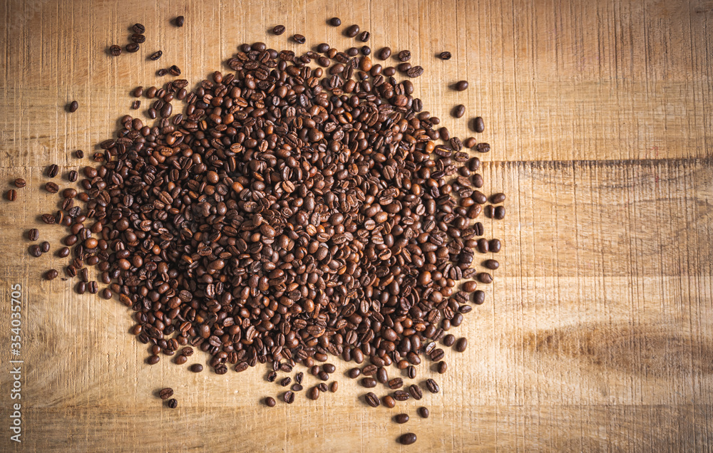 Roasted brown coffee beans spilled on wooden table background. Roasted brown coffee beans spilled on wooden table background.