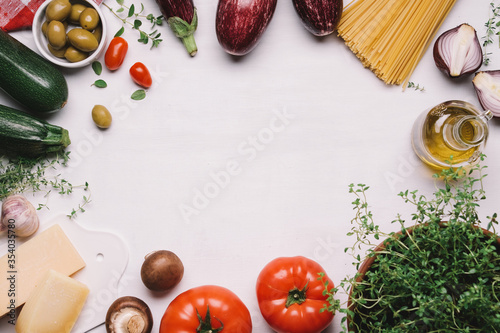 Ingredients of italian food. Spaghetti, tomatoes, olives, olive oil, parmesan, traditional mediterranean vegetables and herbs. White food background