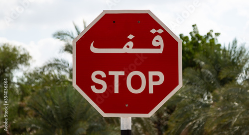 Bilingual arabic-english STOP sign in front of trees in town of Al Mudhairib in Oman photo