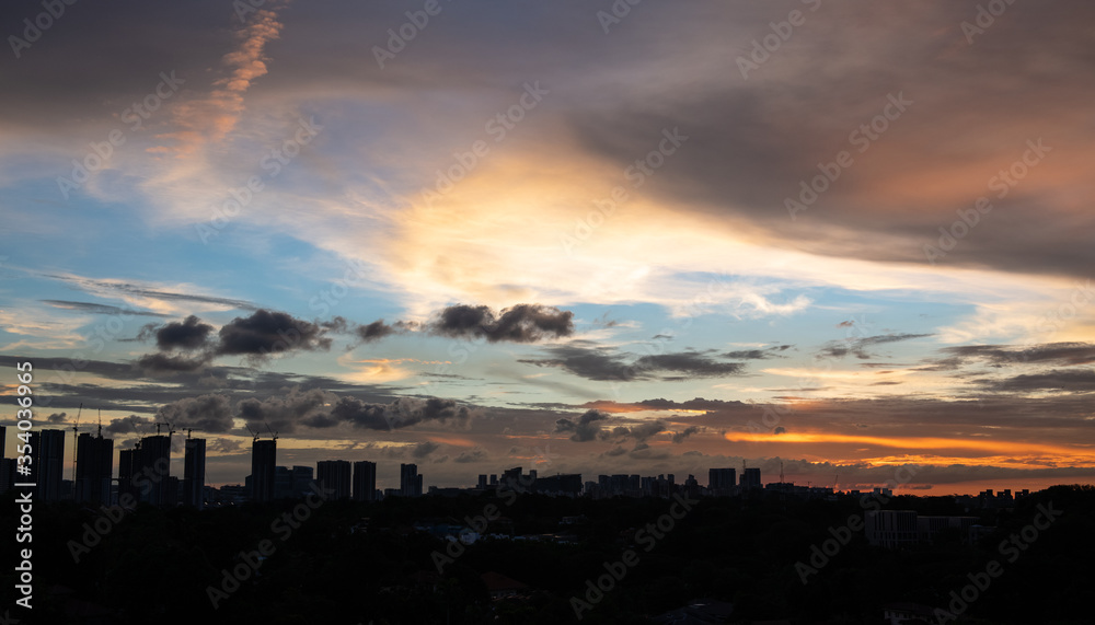 Warm sunset over city landscape with tall buildings and sky scrapers' silhouette in the foreground