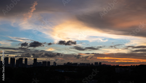 Warm sunset over city landscape with tall buildings and sky scrapers  silhouette in the foreground