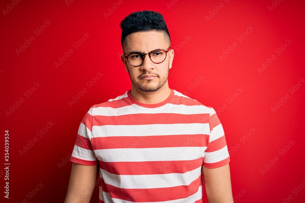 Young handsome man wearing casual striped t-shirt and glasses over isolated red background depressed and worry for distress, crying angry and afraid. Sad expression. Young handsome man wearing casual striped t-shirt and glasses over isolated red background depressed and worry for distress, crying angry and afraid. Sad expression.