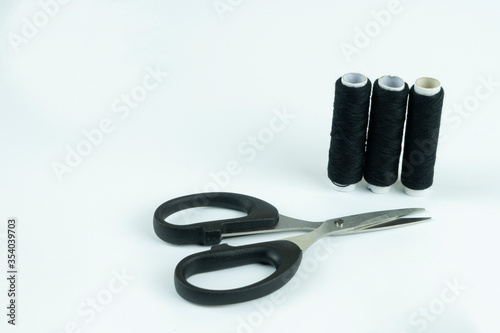 Spools of thread in black and white with scissors on a white background, handmade embroidery