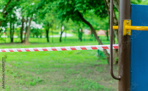 Children's playground wrapped with red barrier tape. Outside. Prohibition of outdoor walks, prevention of the biological hazard of the influenza virus covid-19. coronavirus. selective focus