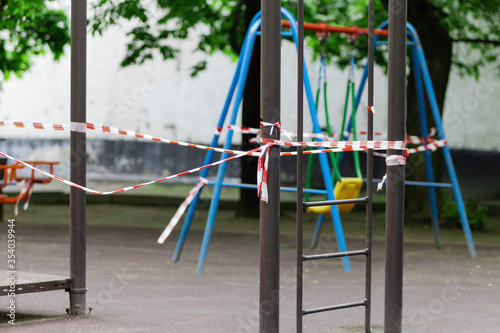 The play park of amusement and sports for young children is wrapped in red barrier tape. Prohibition of outdoor walks, prevention of the coronavirus influenza virus covid-19. colorful. selective focus