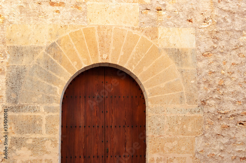Stone facade with wooden door and stone arch of popular architecture © Nemesio
