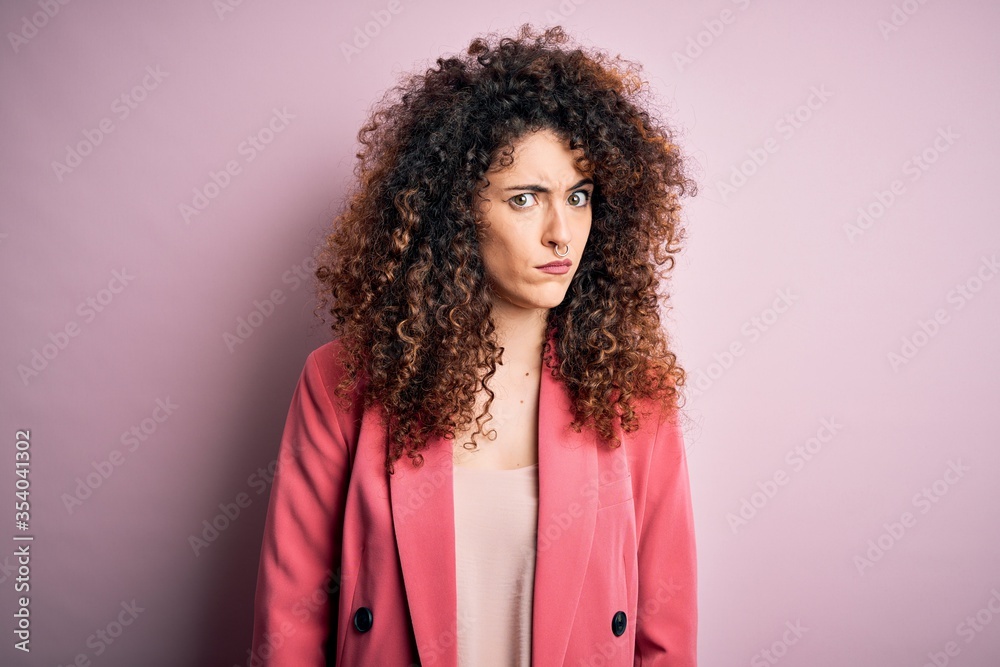 Young beautiful businesswoman with curly hair and piercing wearing elegant jacket skeptic and nervous, frowning upset because of problem. Negative person. Young beautiful businesswoman with curly hair and piercing wearing elegant jacket skeptic and nervous, frowning upset because of problem. Negative person.
