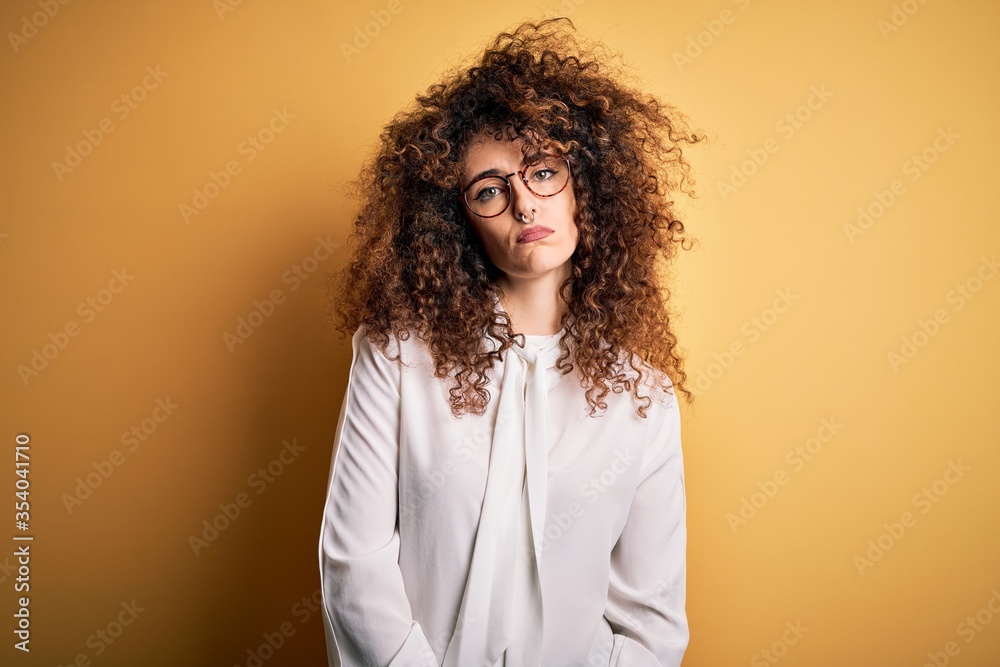 Young beautiful brunette woman with curly hair and piercing wearing shirt and glasses depressed and worry for distress, crying angry and afraid. Sad expression.