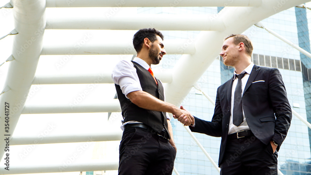 business people standing with handshake in front of building business people standing with handshake in front of building
