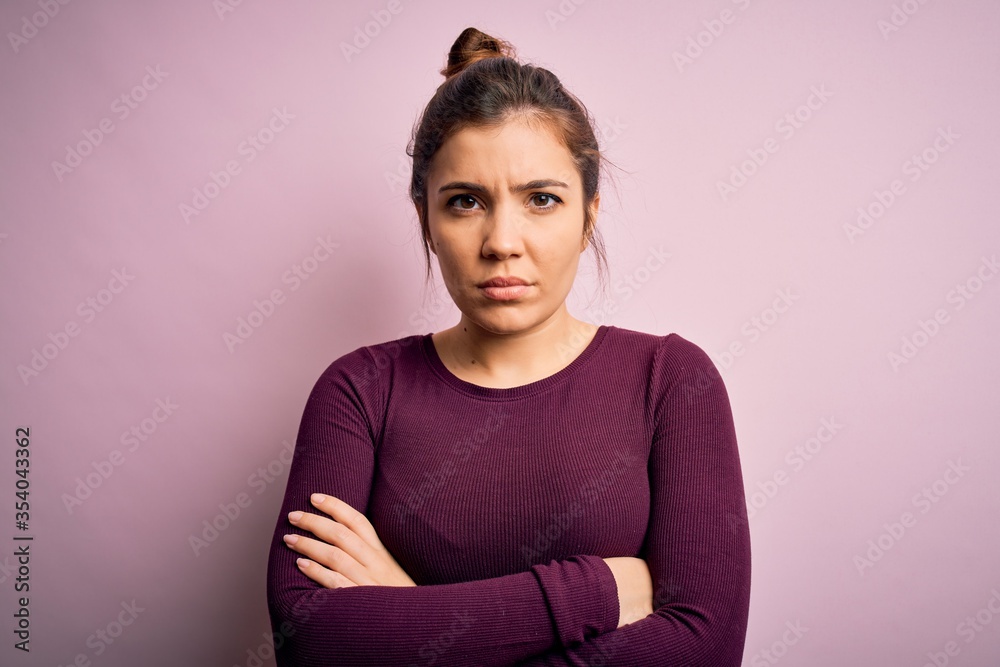 Beautiful young woman wearing casual bun hairstyle over pink isolated background skeptic and nervous, disapproving expression on face with crossed arms. Negative person.
