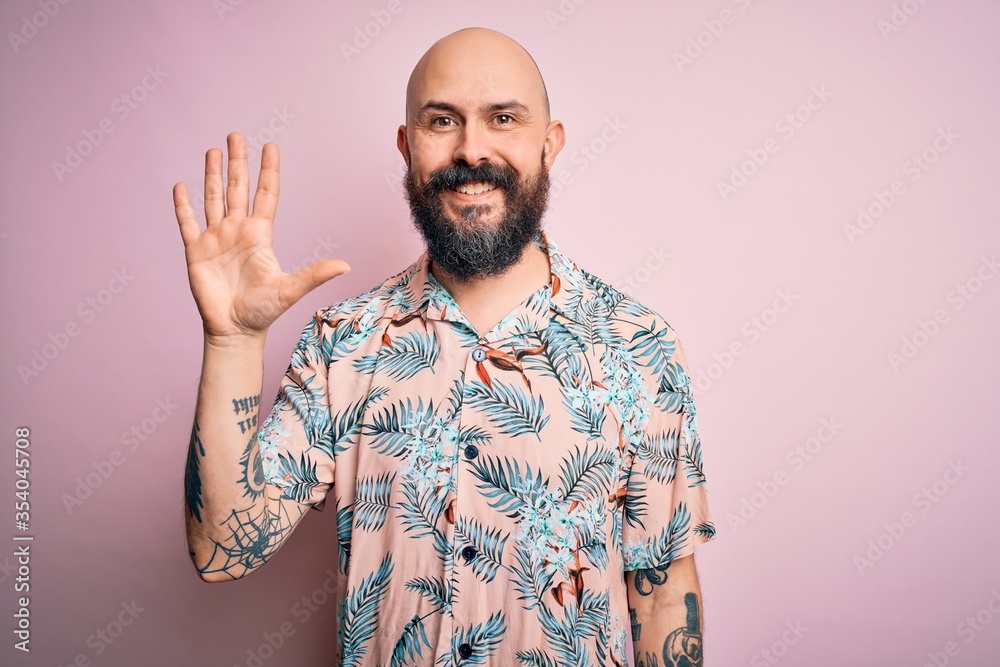 Handsome bald man with beard and tattoo wearing casual floral shirt over pink background showing and pointing up with fingers number five while smiling confident and happy. Handsome bald man with beard and tattoo wearing casual floral shirt over pink background showing and pointing up with fingers number five while smiling confident and happy.