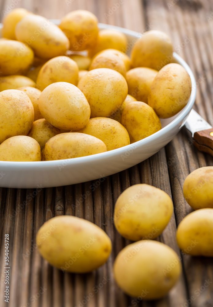 Fresh organic small potatoes in bowl with knife on wooden background Fresh organic small potatoes in bowl with knife on wooden background
