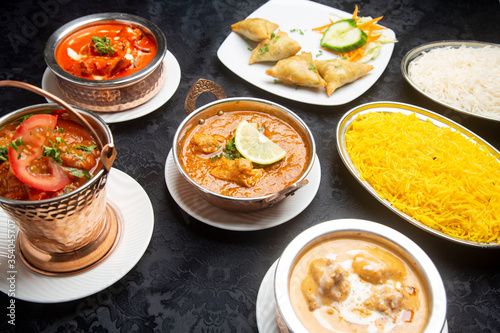 Table with typical Indian dishes, chicken curry, tandoori, tikka masala, korma, pilaf rice.